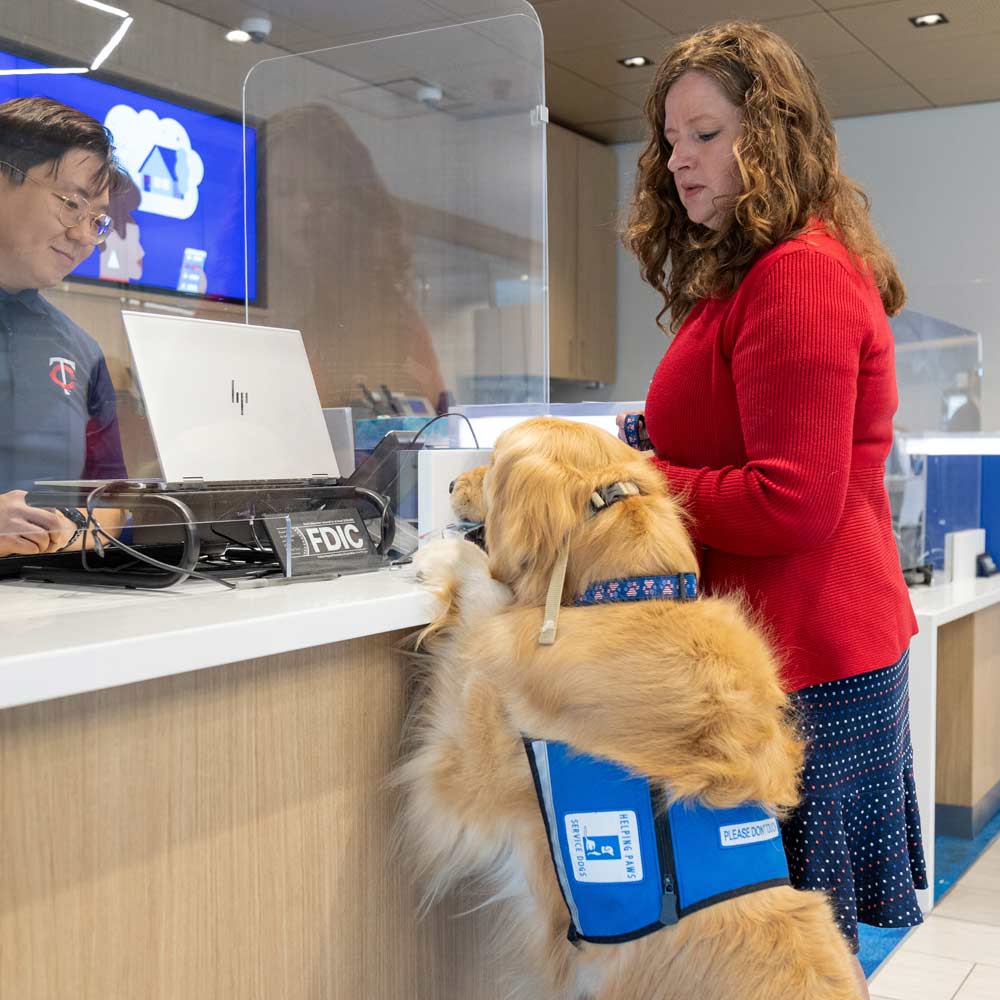 Woman at a bank branch with a service dog holding her ATM card